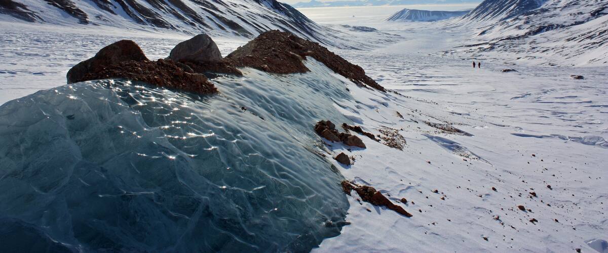 A glacier with large ice formations and snow-covered mountains.