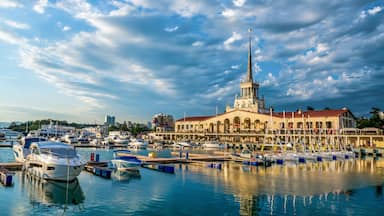 A marina with boats docked, a prominent tower, and a building with arches.