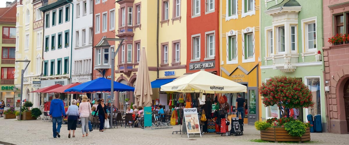 A colorful street with cafes and shops, a sign for 'spitznagel', and a 'United Colors of Benetton' store.