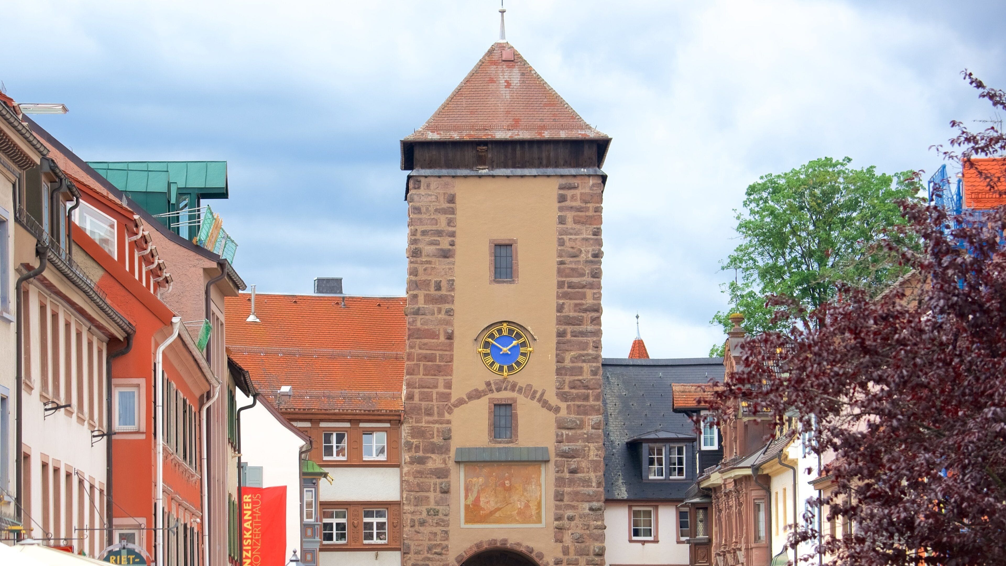 A historic tower with a clock, surrounded by colorful buildings.