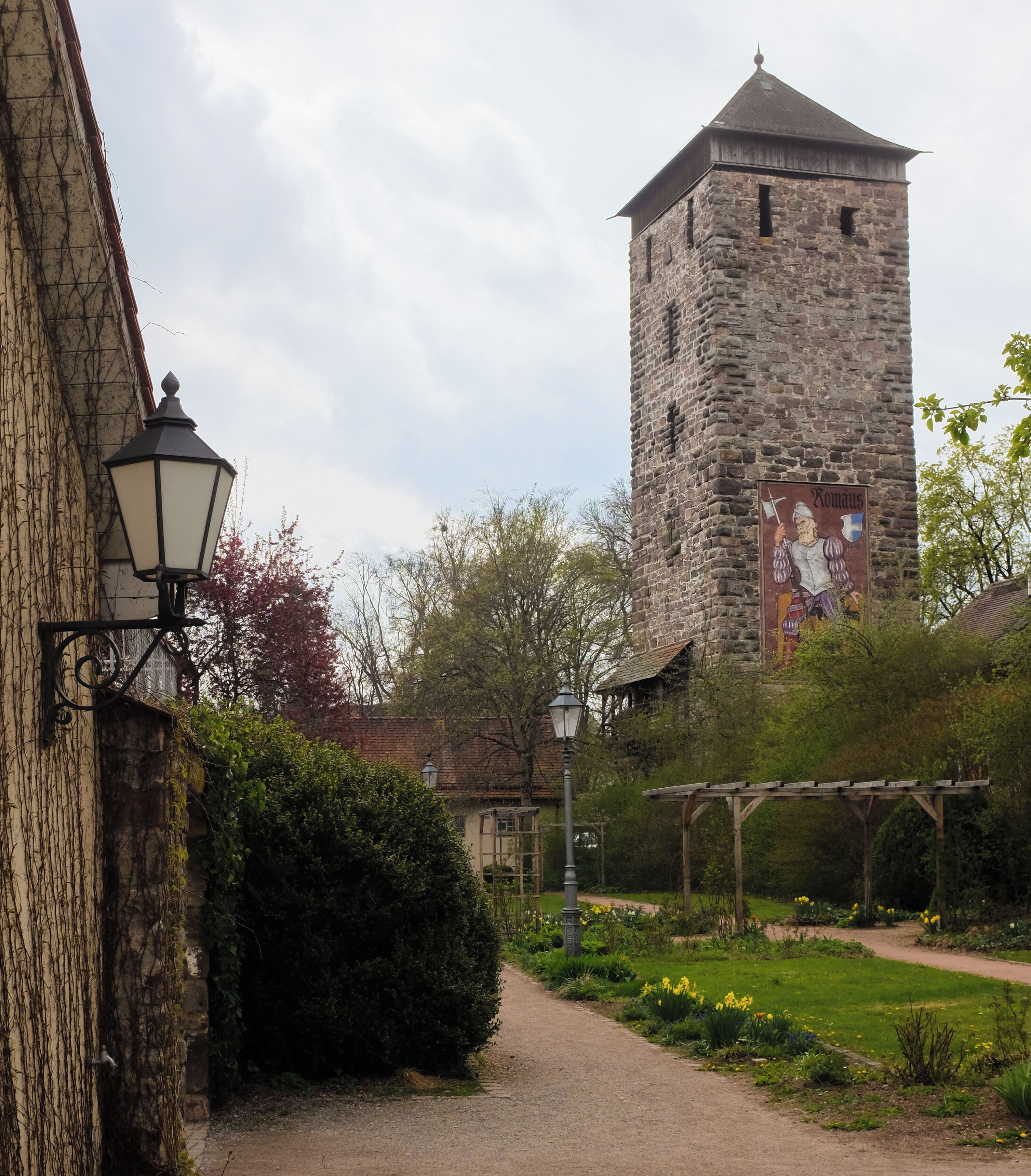 A stone tower, a garden, and a building with ivy.