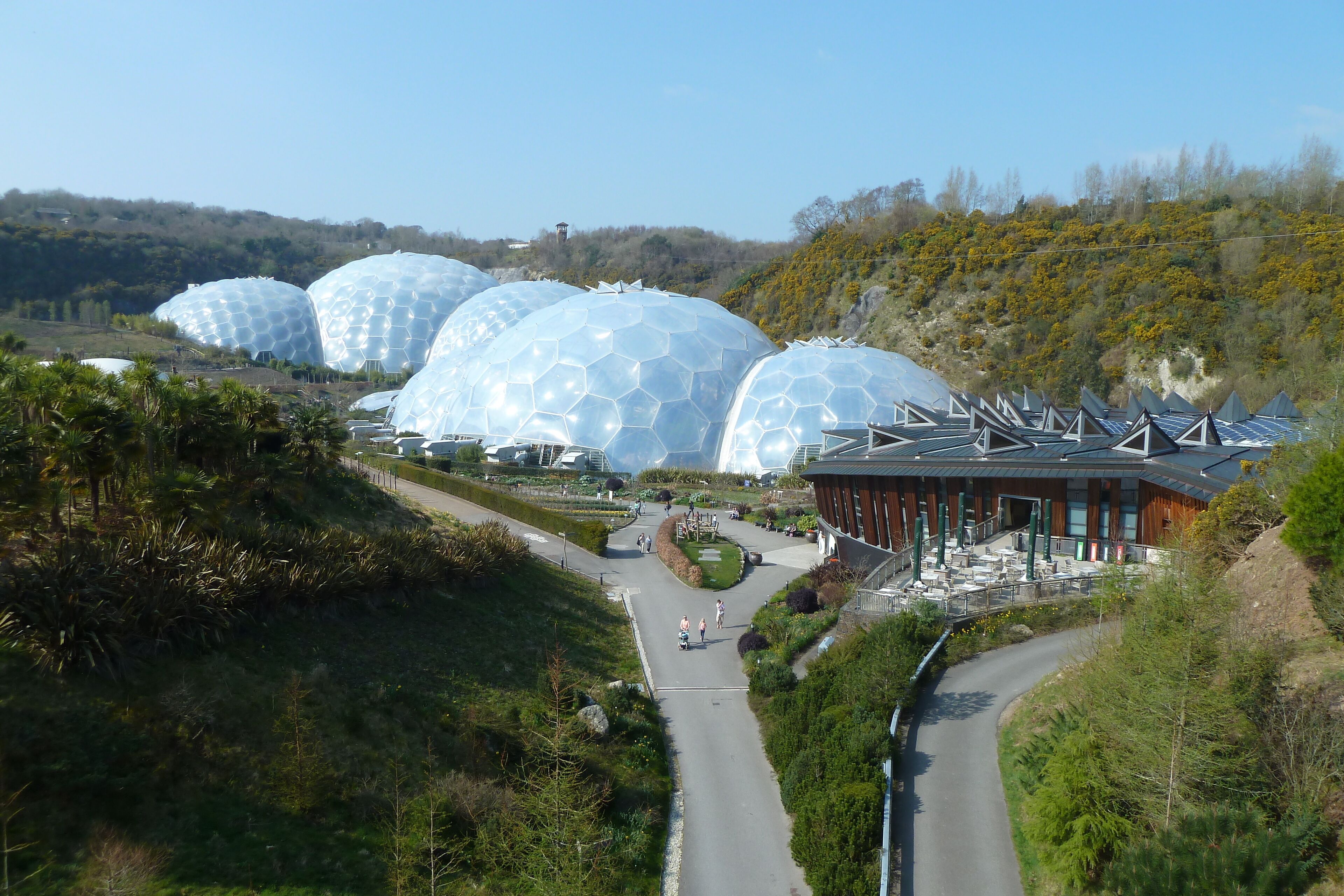 A landscape with large geodesic domes and a modern building with a sloped roof.