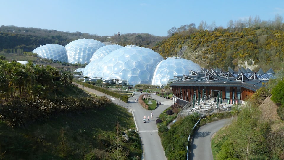 A landscape with large geodesic domes and a modern building with a sloped roof.