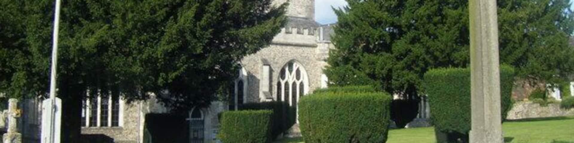 A church with a tall tower, a large cross, and well-maintained lawns.