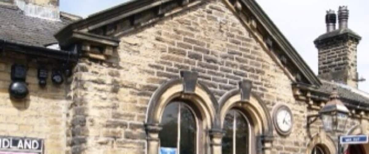 A stone building with a clock, a bench, and a sign that reads "OAKWORTH."