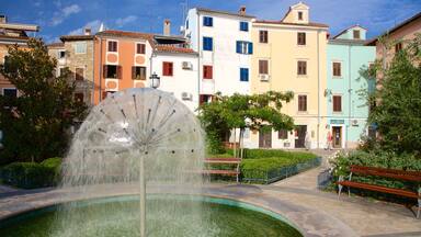 A fountain with a large circular water feature in a public square surrounded by colorful buildings.