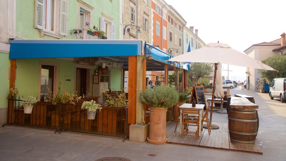 A quaint outdoor cafe with wooden tables and chairs, potted plants, and a large umbrella.