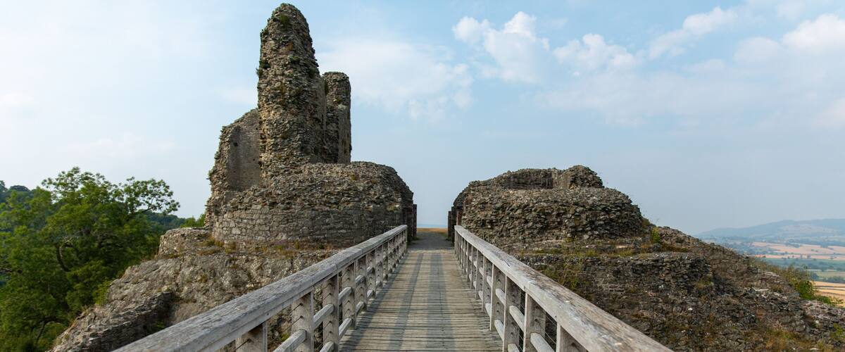 A stone pathway leading to ancient ruins with a wooden railing.