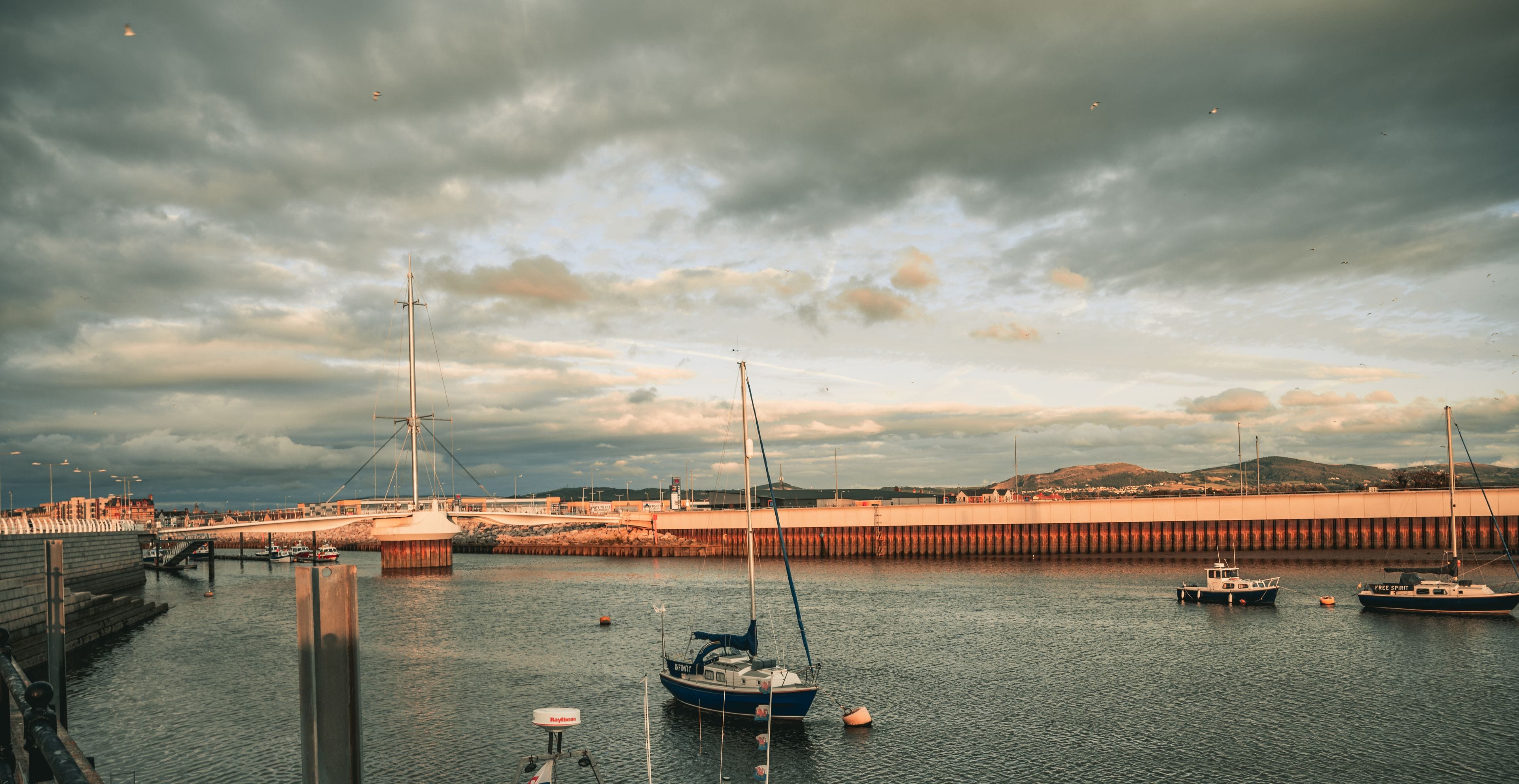 A harbor with boats, a bridge, and a cloudy sky.