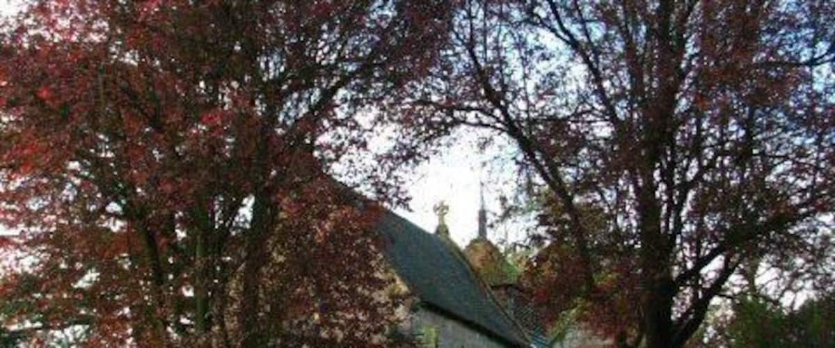 A church with a stone facade, surrounded by a well-maintained lawn and trees with autumn leaves.