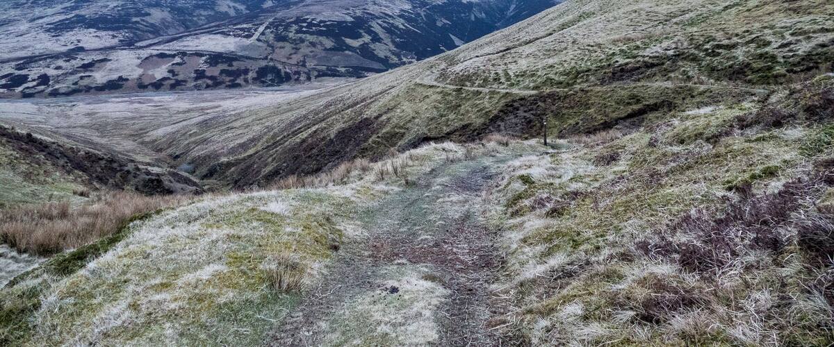 A mountainous landscape with a trail and distant hills.