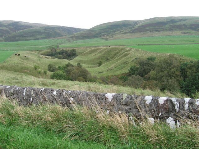 Colinas onduladas, un muro de piedra y un campo verde.