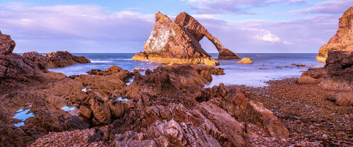 A rocky coastline with prominent rock formations and a clear sky.