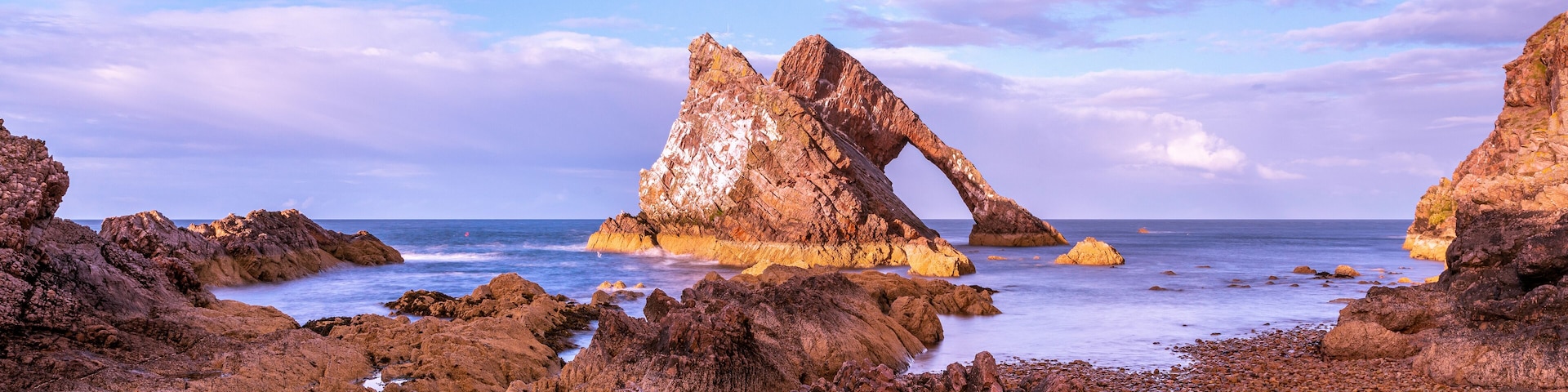 A rocky coastline with prominent rock formations and a clear sky.