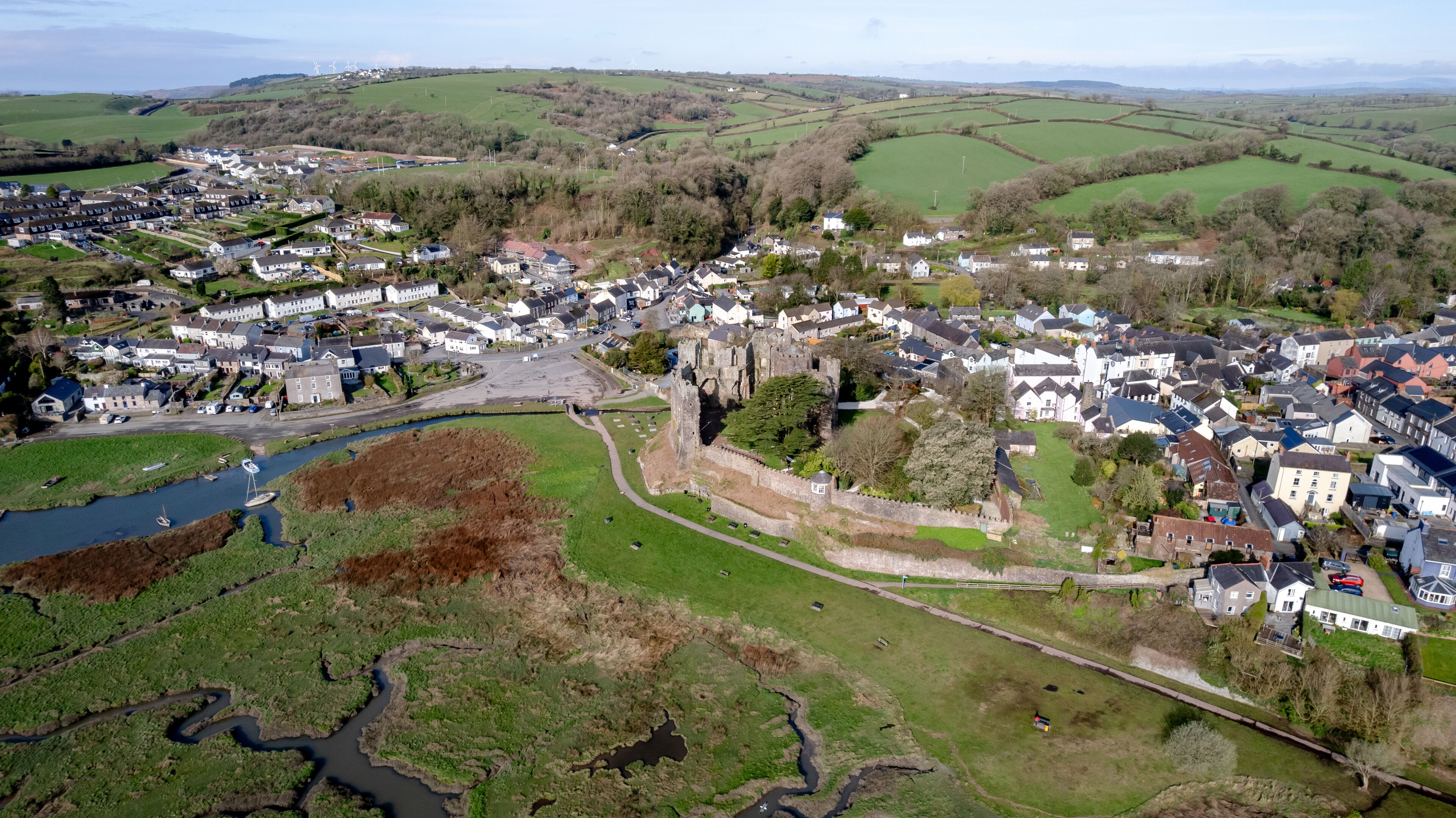 A town with a castle, green fields, and a river.