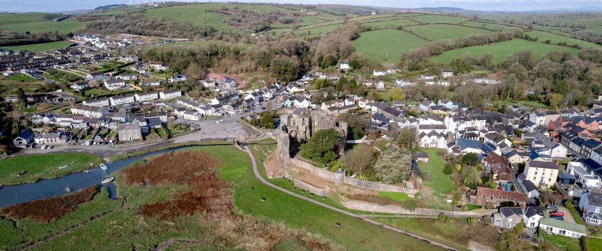 A town with a castle, green fields, and a river.