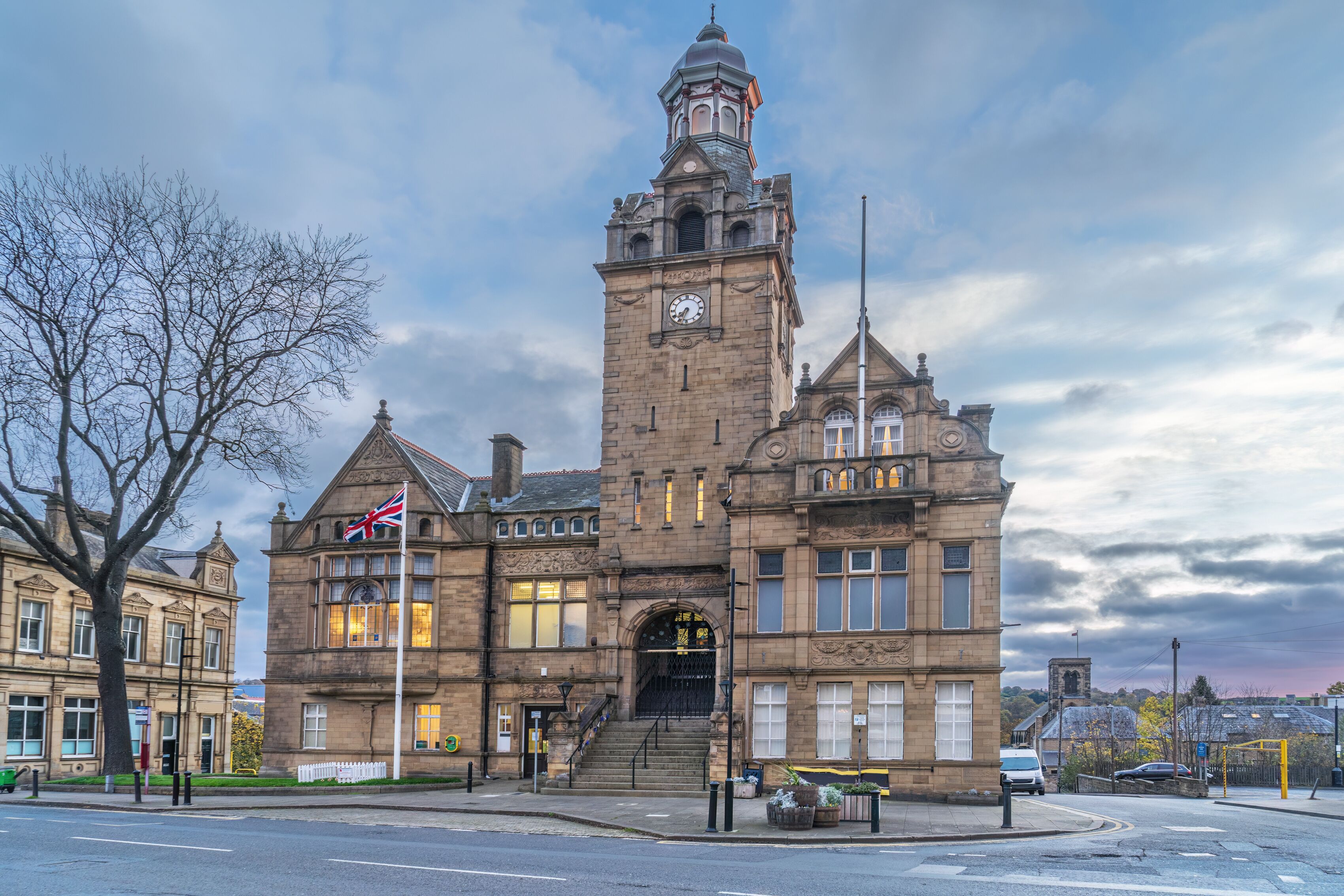 A historic building with a clock tower, flag, and steps leading to the entrance.