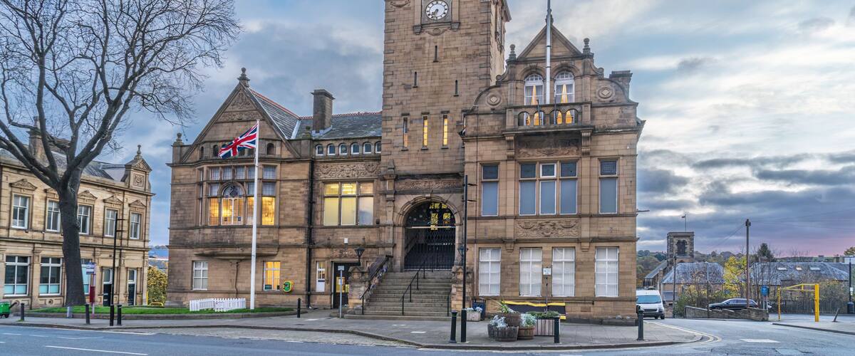 A historic building with a clock tower, flag, and steps leading to the entrance.