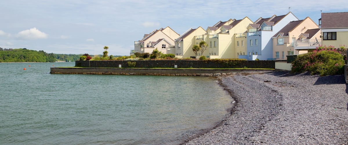 A coastal residential area with houses along a pebble beach and a calm sea in the background.