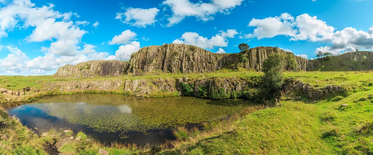 A rocky cliff with a pond reflecting the sky.