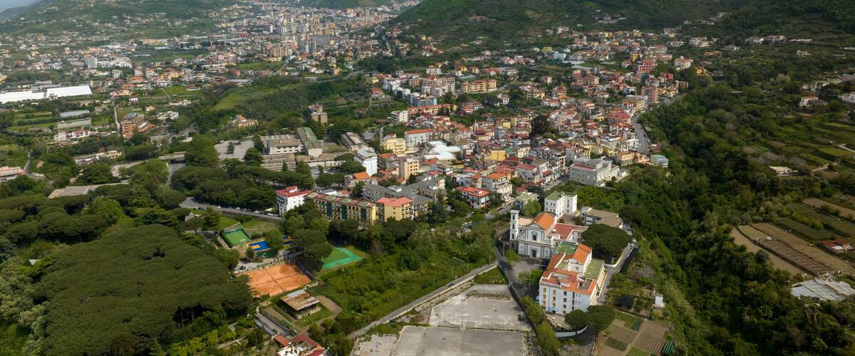 A mountainous town with dense housing and green hills.