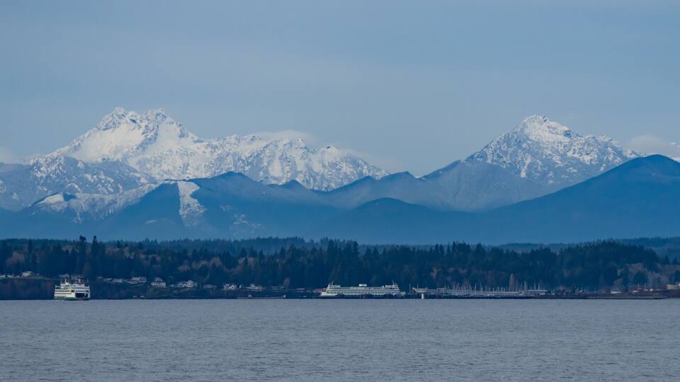 A ferry in a fjord with snow-capped mountains in the background.