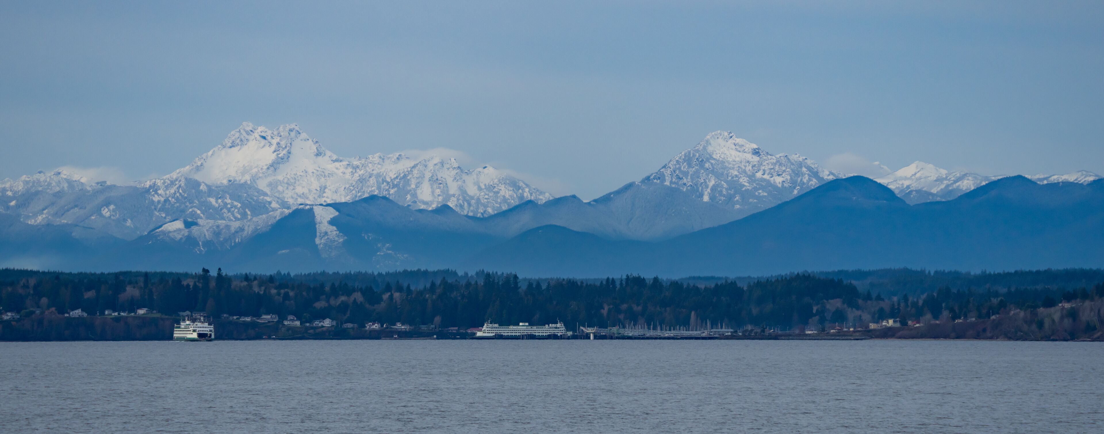 A ferry in a fjord with snow-capped mountains in the background.