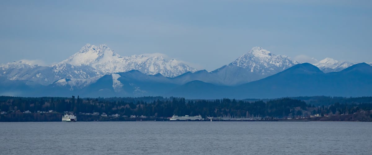 A ferry in a fjord with snow-capped mountains in the background.