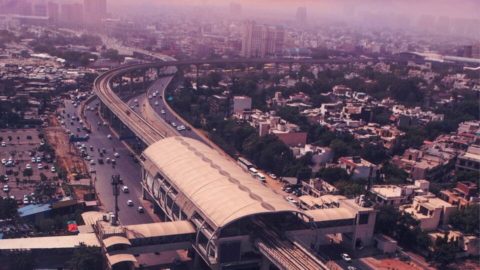 An aerial view of a city with a large overpass and busy roads during sunset.