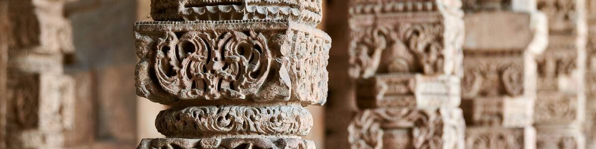 Stone columns with decorative bas relief of Qutb complex in South Delhi, India, close up pillars in ancient ruins of mosque landmark, popular touristic spot in New Delhi, ancient indian architecture