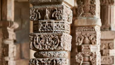 Stone columns with decorative bas relief of Qutb complex in South Delhi, India, close up pillars in ancient ruins of mosque landmark, popular touristic spot in New Delhi, ancient indian architecture