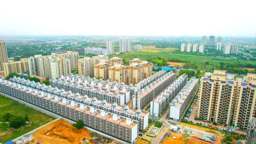 aerial drone shot symmetrically placed flats, houses, with skyscrapers at the back showing mass produced modular homes growing the real estate segment
