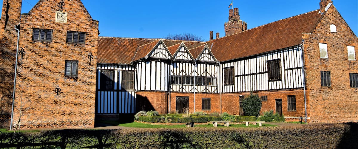 A historic building with Tudor-style architecture, featuring brick walls and timber framing.
