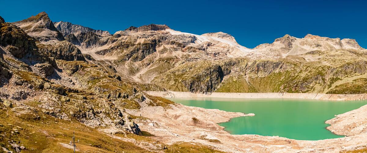 A mountain landscape with a turquoise lake, rocky terrain, and a cable car system.
