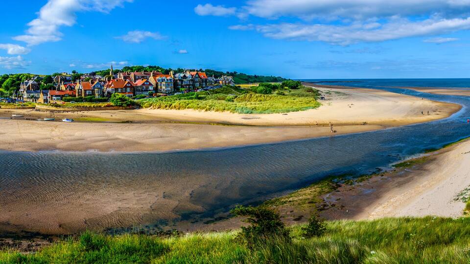 A coastal town with houses, a beach, and a bay.
