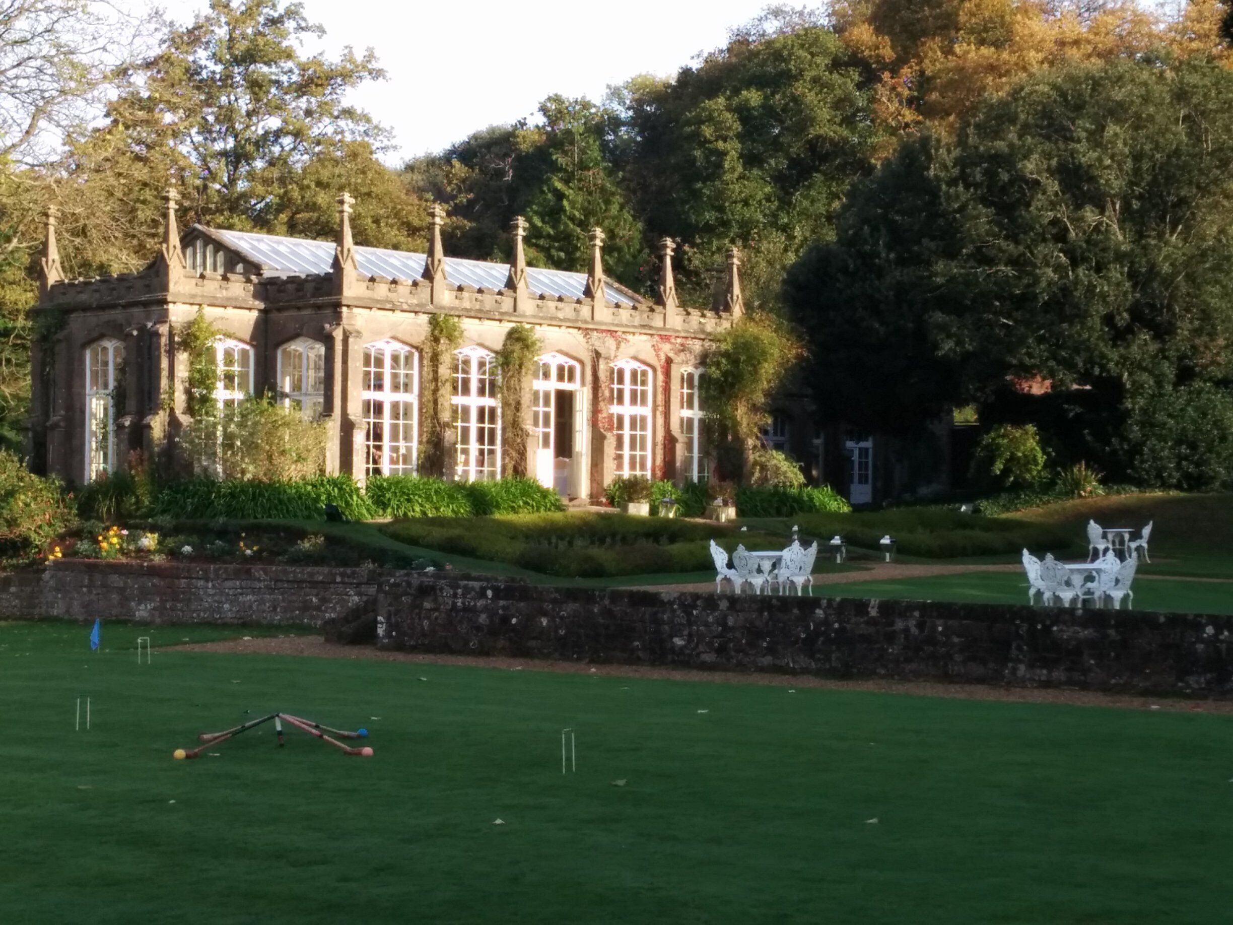 A historic building with large windows and a garden with white furniture.