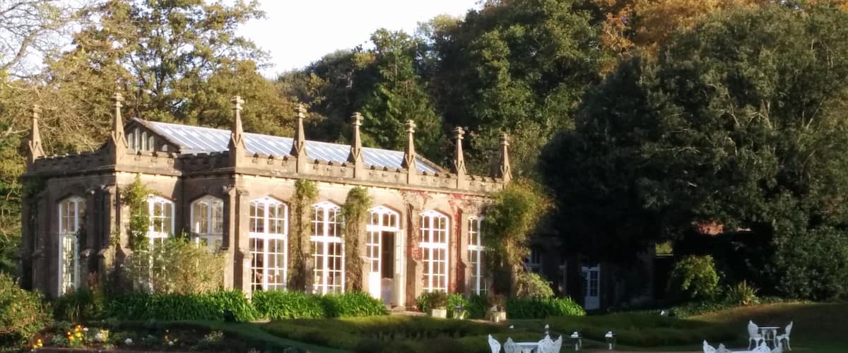 A historic building with large windows and a garden with white furniture.