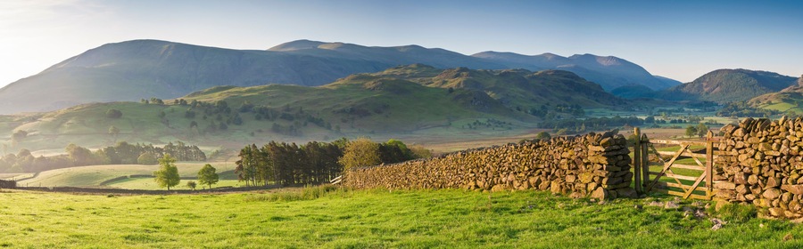 A green valley with stone walls and a mountain range in the background.