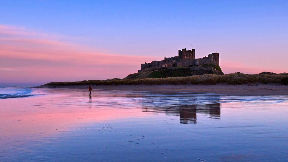 A castle on a beach at sunset.