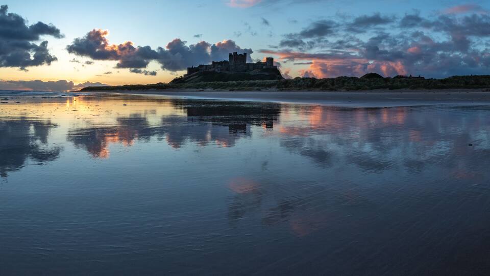 A beach with a castle in the background during sunset.
