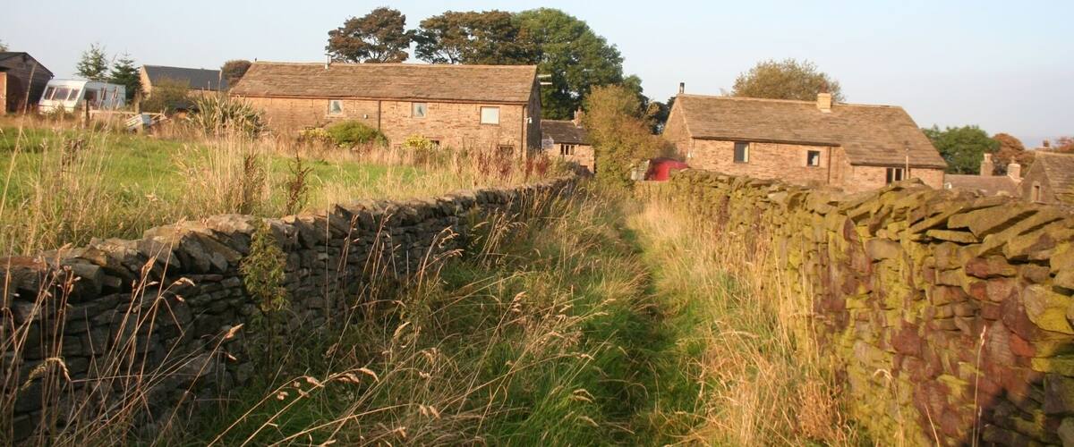 A rural landscape with stone walls, grassy fields, and traditional stone houses.