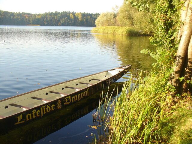 Ein hölzernes Boot liegt an einem Steg, mit der Aufschrift 'Latefide & Dragon'.