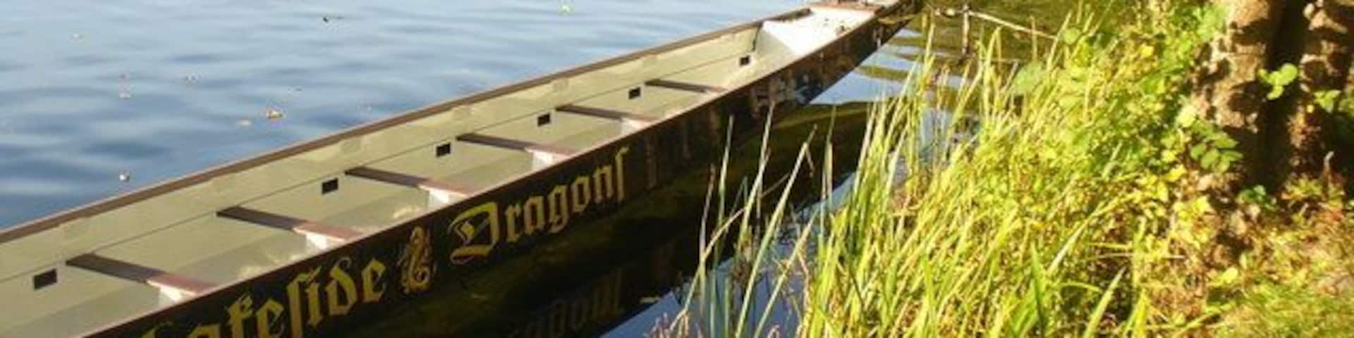 A wooden boat docked at a pier with the inscription "Latefide & Dragon."