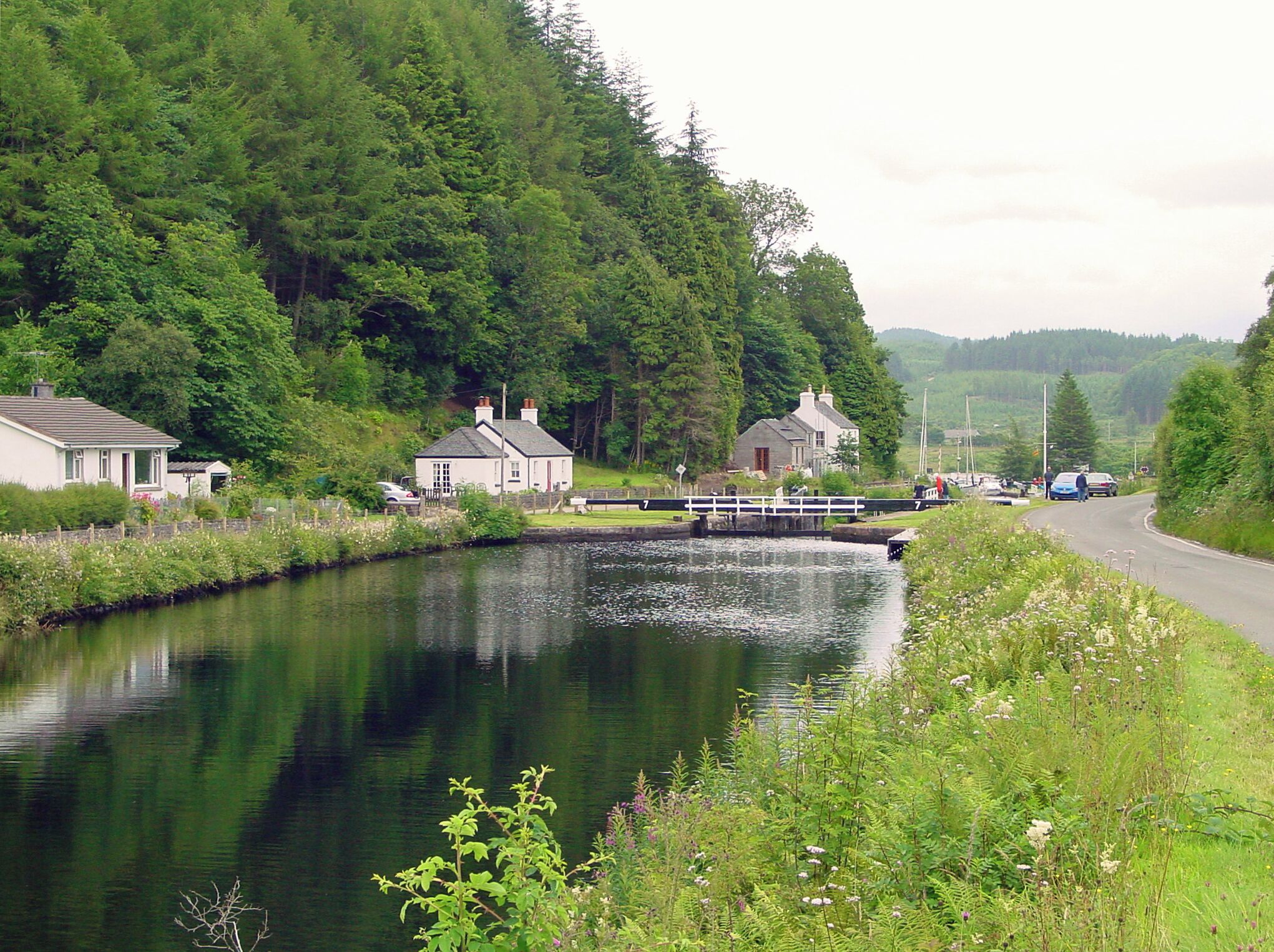 A narrow waterway flanked by lush greenery and small houses.