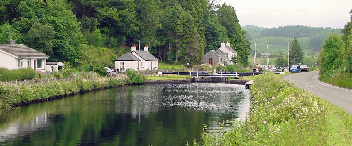 A narrow waterway flanked by lush greenery and small houses.