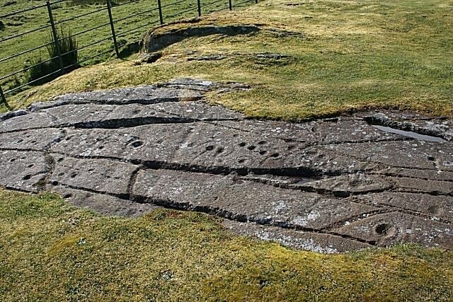 Cup-and-Ring-Marked Rock This is one of three rock surfaces in the immediate vicinity which have incised cup-and-ring marks. The shape formed by the long cracks on this one are sometimes described as a fish, but to me most of them look too deep to have been carved with the primitive tools of 5000 years ago. Perhaps a prehistoric carver also noticed the natural shape, and enhanced it by adding s few extra lines.