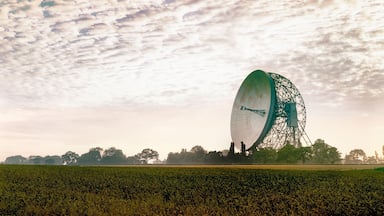 A large circular structure in a field with a cloudy sky.
