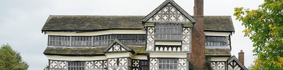 Ein im Tudor-Stil gehaltenes Gebäude mit einer weiß-schwarz gefärbten Fachwerkfassade, einem Ziegelkamin und einem gepflasterten Weg zum Eingang.