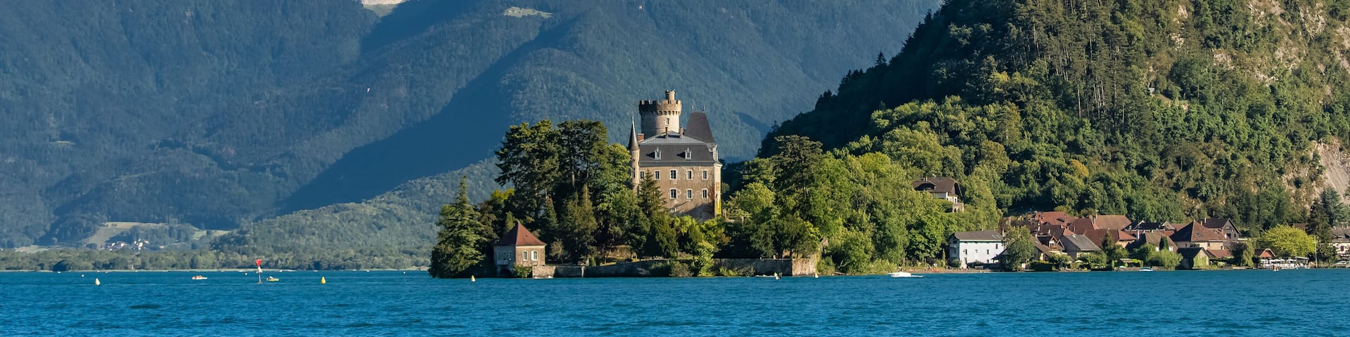 A castle on an island surrounded by a lake and mountains.