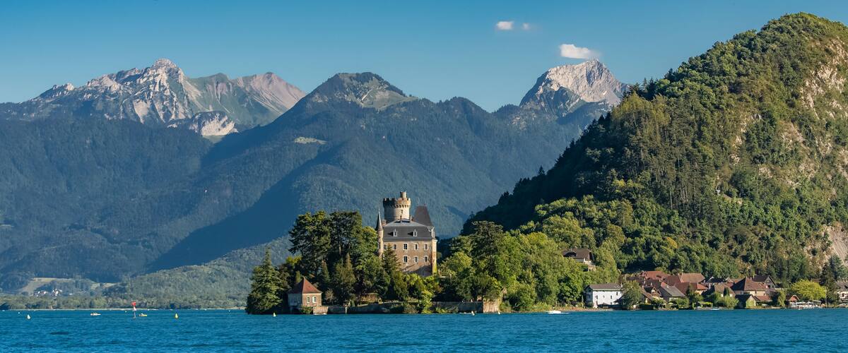 A castle on an island surrounded by a lake and mountains.